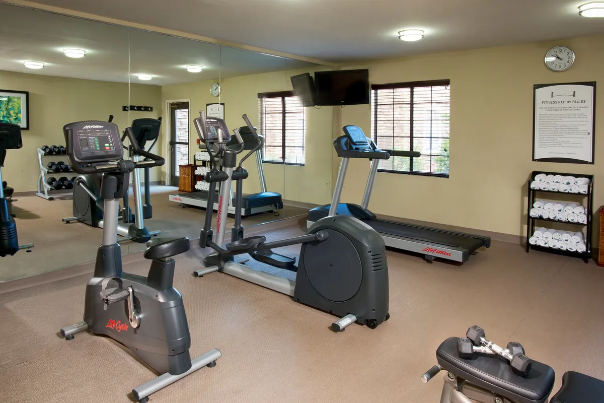 A bright interior shot of the on-site fitness center, with exercise equipment, a mirrored wall, and neatly stacked towels. Fitness guidelines are visible, creating a motivating yet approachable atmosphere for guests focused on maintaining their wellness routines.
