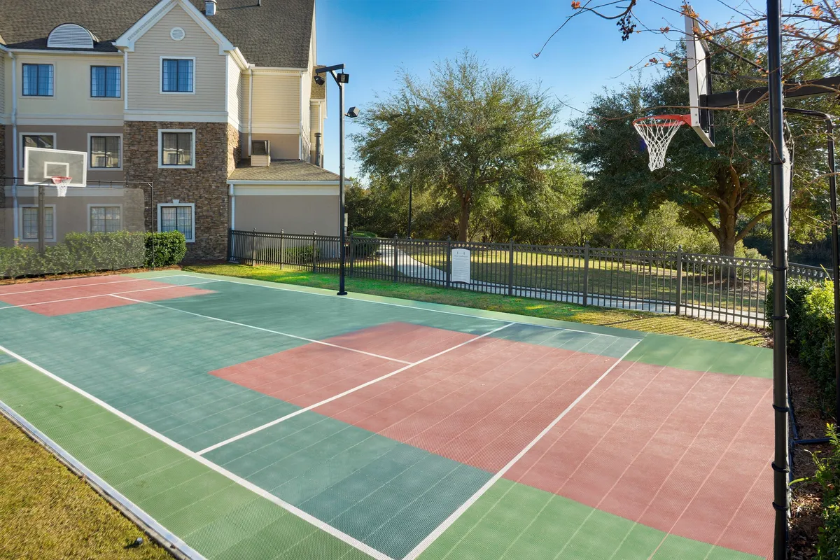This image highlights a basketball court surrounded by greenery. The scene feels active and playful, with the setting suggesting options for outdoor exercise or casual play, supporting a balanced business trip.