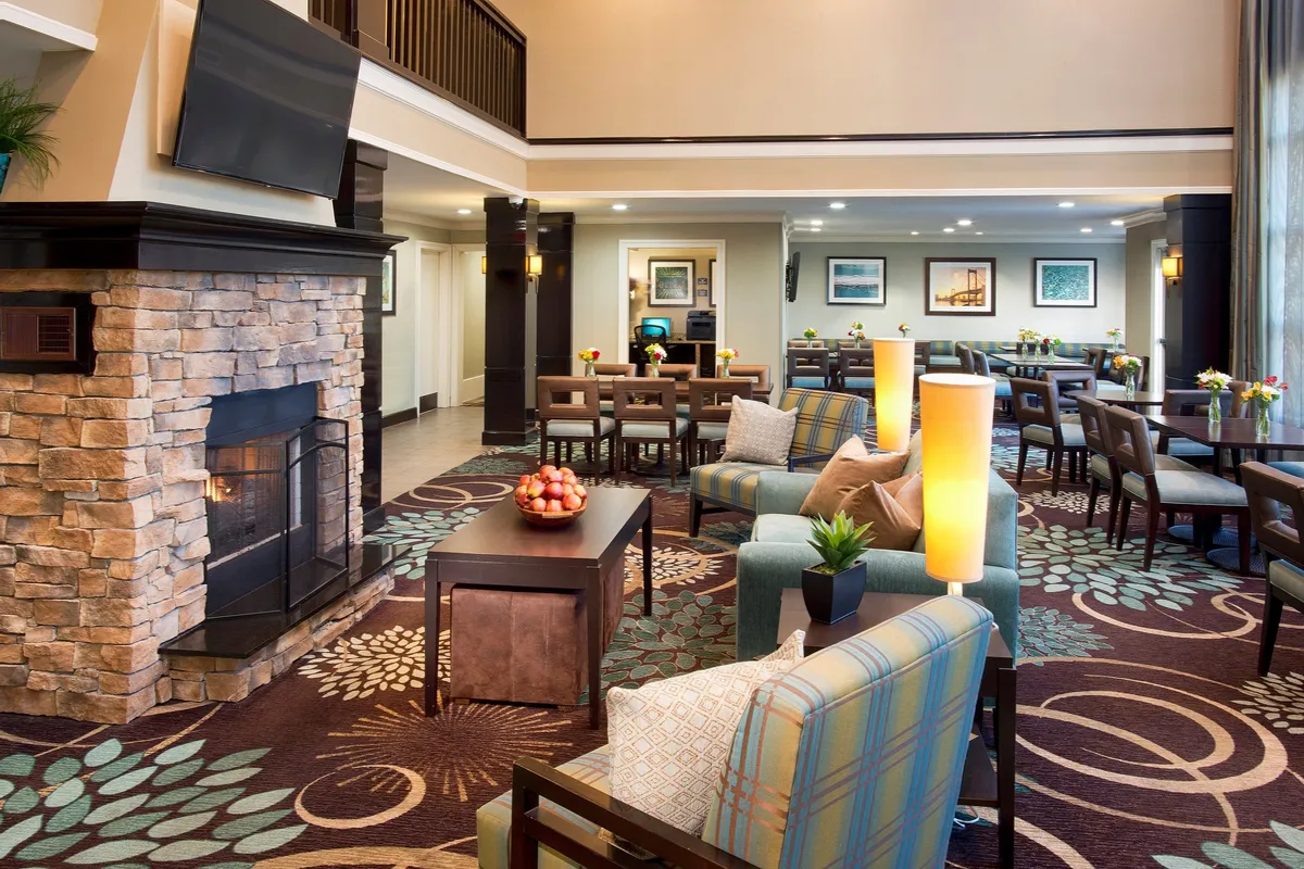 A cozy, tastefully decorated living area is shown with a fireplace, comfortable seating, a dining table, and decorative plants. The space exudes warmth and relaxation, providing an inviting setting for unwinding or getting work done.