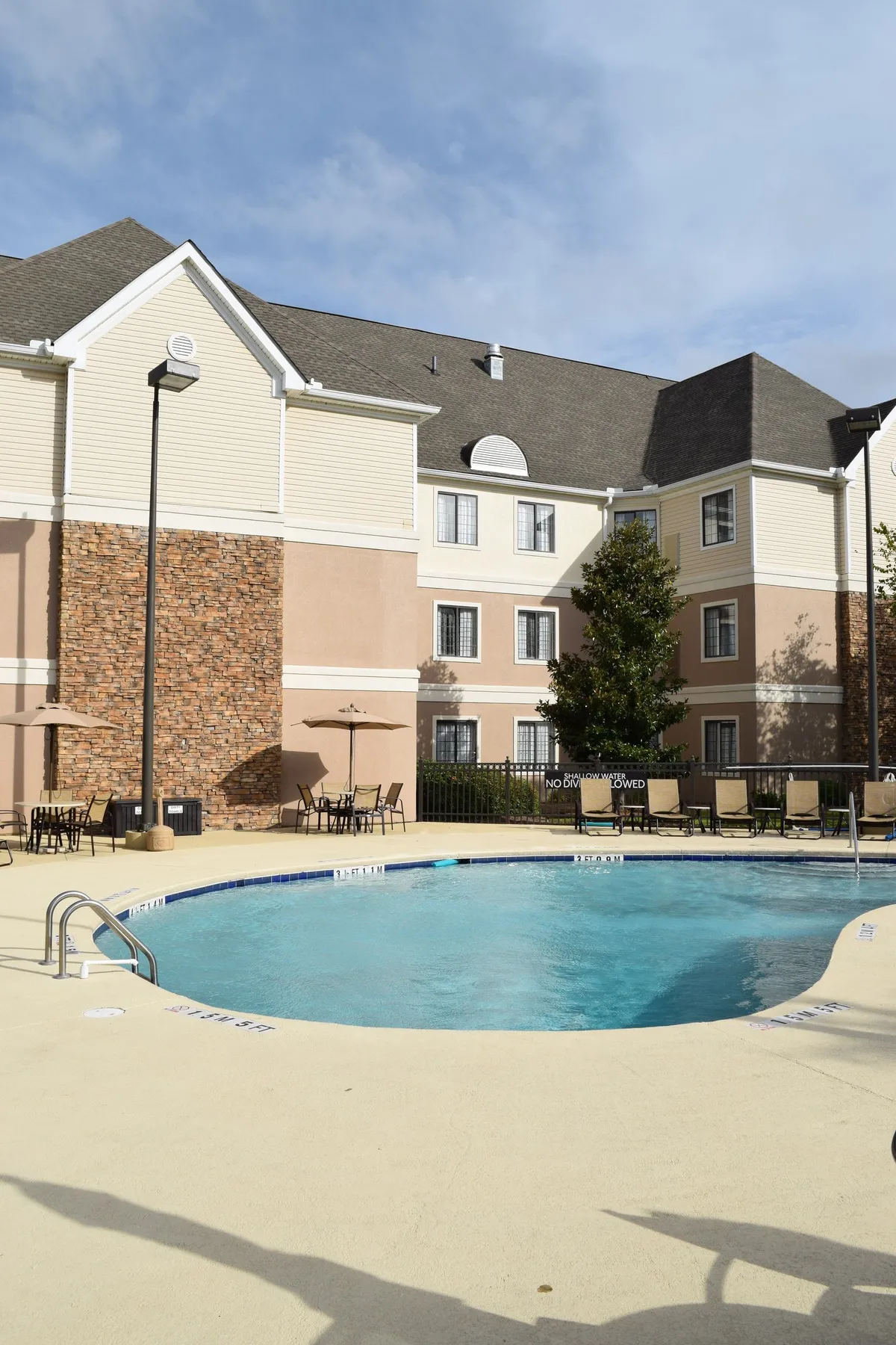 This scene shows the hotel’s outdoor swimming pool area, with plenty of comfortable seating and the building facade in view. The relaxed ambiance is enhanced by details like morning sunlight reflecting on the water, people lounging, and the overall peaceful setting—ideal for starting or ending a day of adventure.