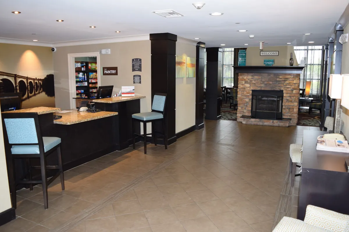 This interior image features the front desk area, a cozy fireplace, and a pantry space. The friendly staff at the desk and the inviting common area set the tone for attentive guest services and a comfortable daily routine.