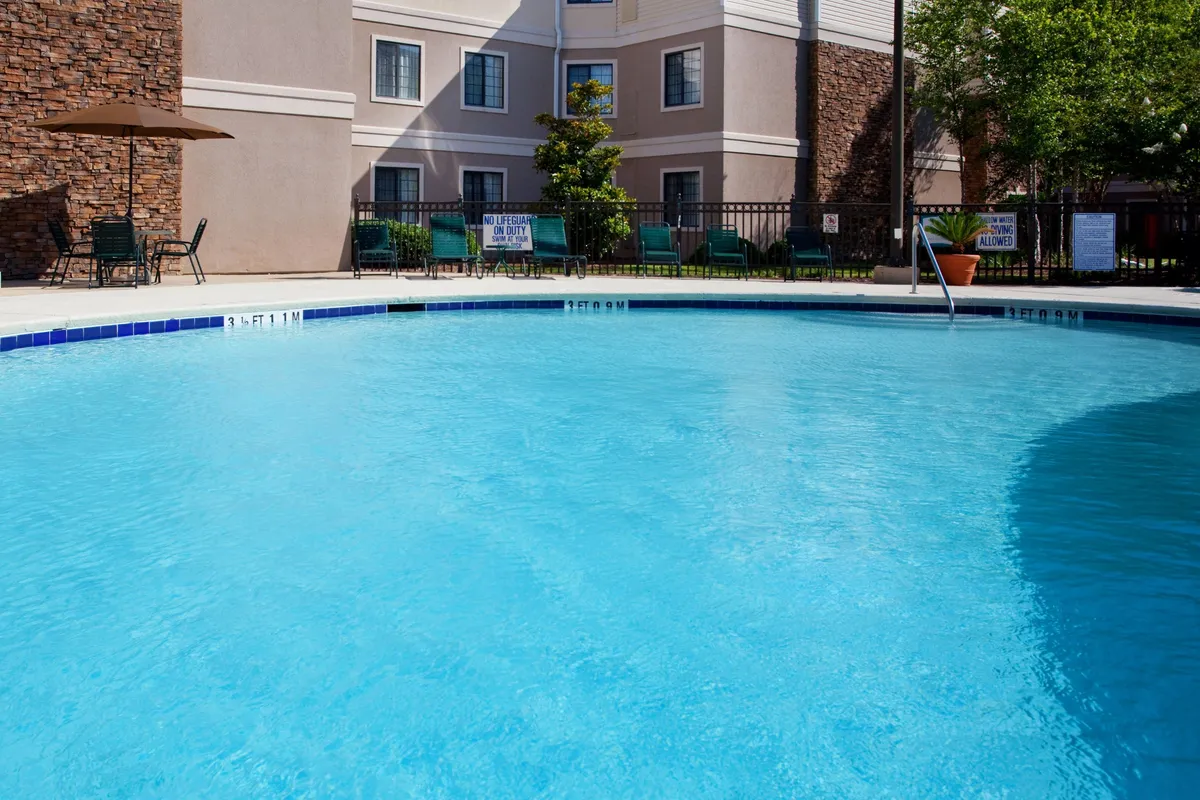 This exterior scene captures the swimming pool area with inviting outdoor seating, the hotel building facade in the background, and a refreshing, leisurely mood. The setting conveys relaxation options for guests after a productive day.